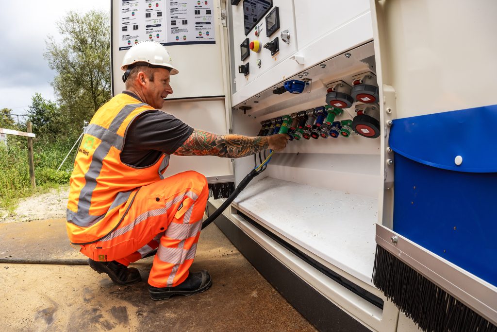 Construction worker connecting machine to battery container